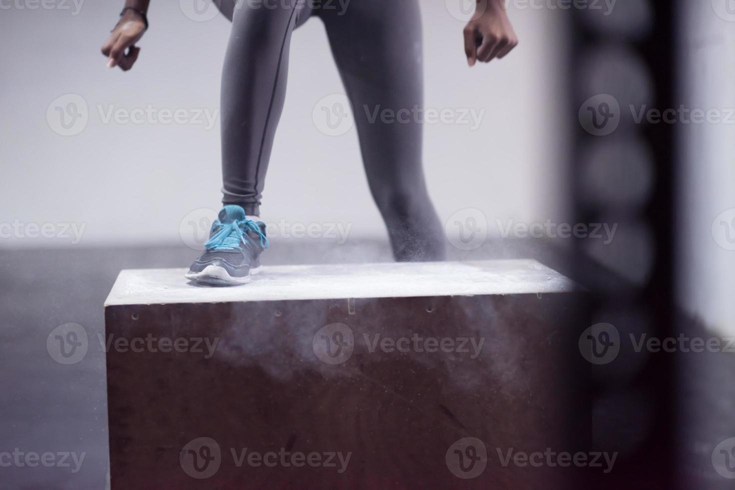 Schwarze Frau führt Boxsprünge im Fitnessstudio durch foto