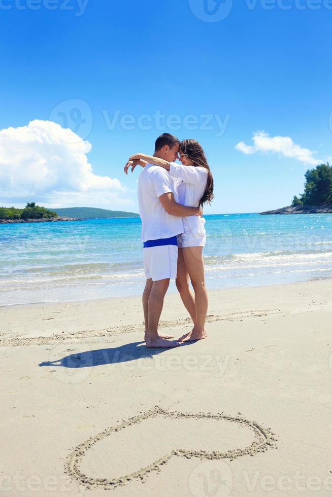 romantische verliebte paare haben spaß am strand mit herzzeichnung auf sand foto