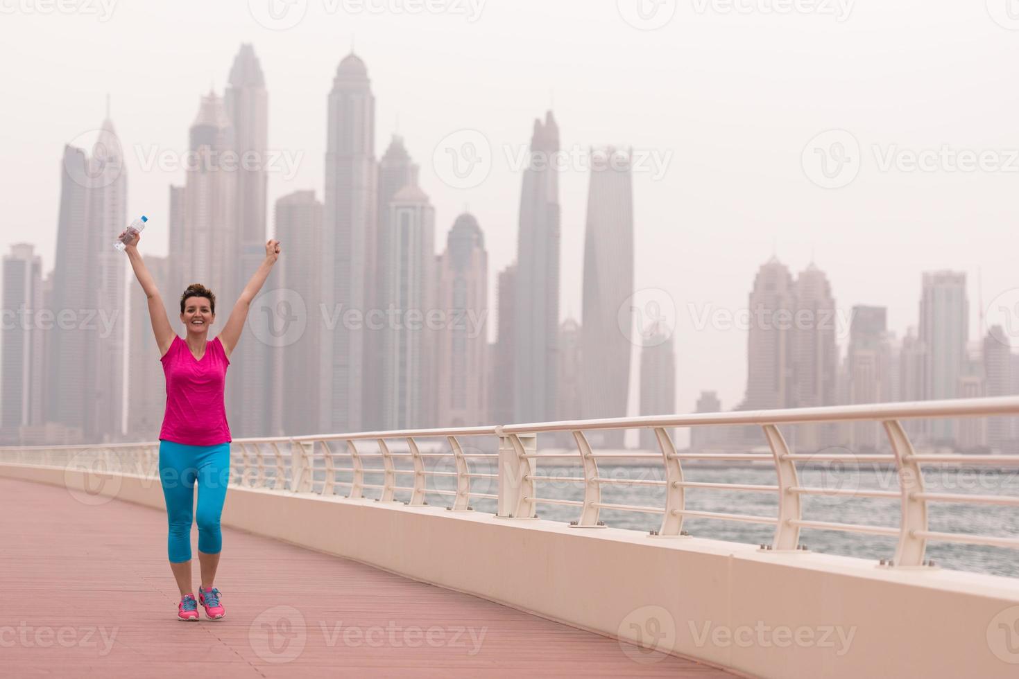 junge Frau, die einen erfolgreichen Trainingslauf feiert foto