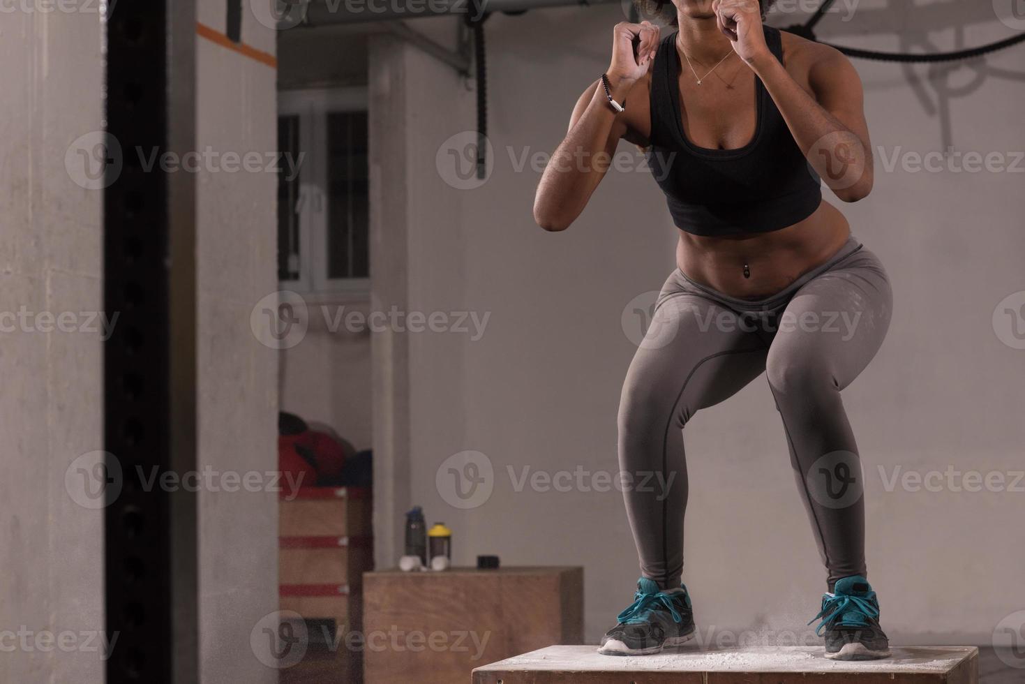 Schwarze Frau führt Boxsprünge im Fitnessstudio durch foto