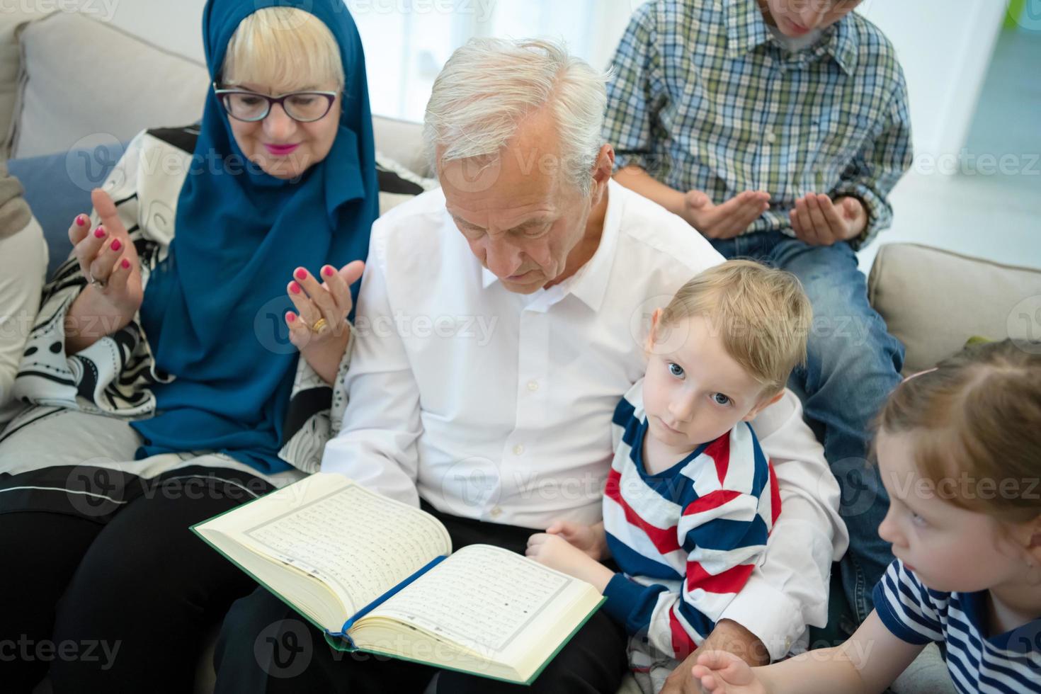 moderne muslimische großeltern mit enkelkindern, die den koran lesen foto