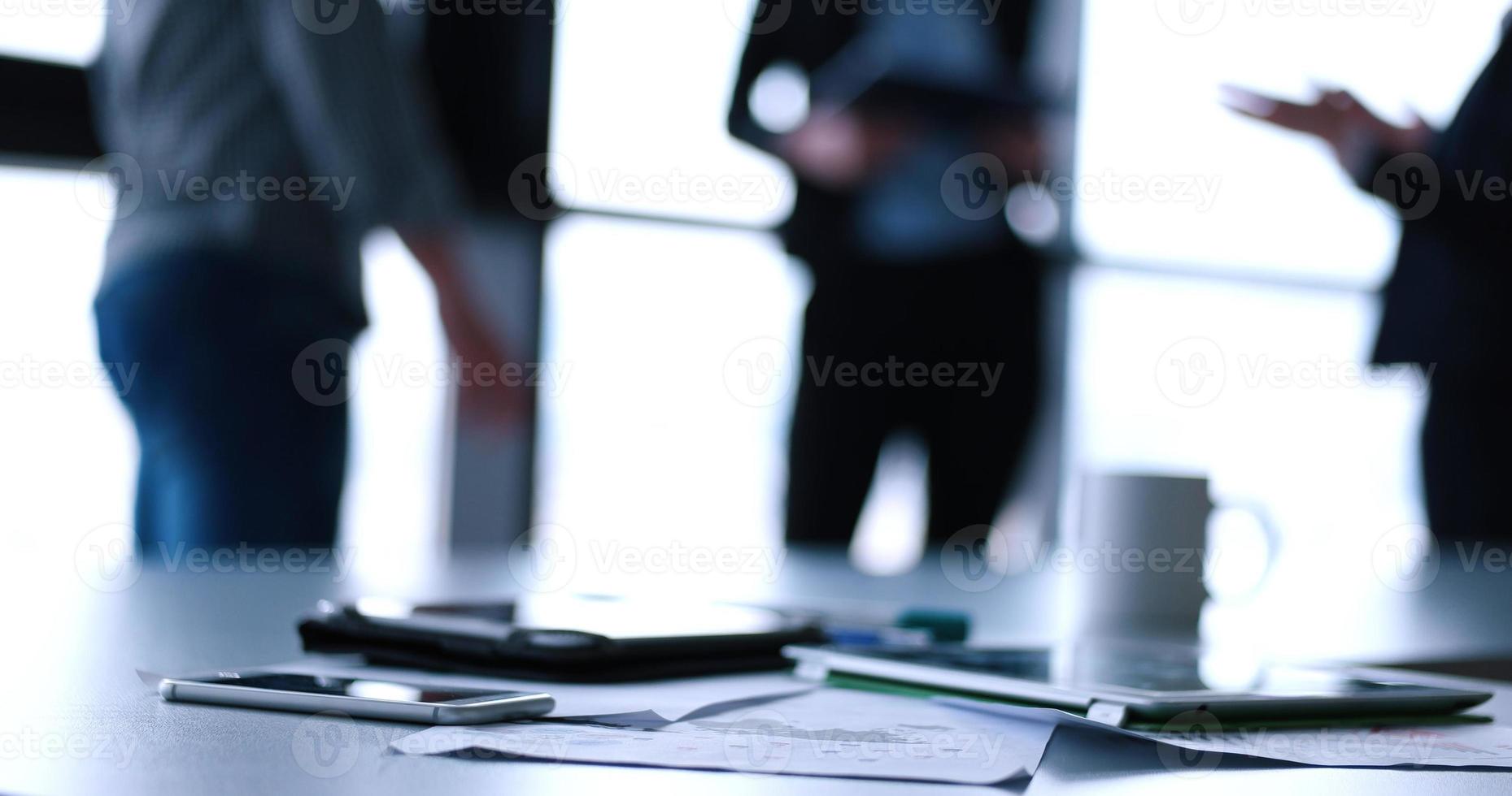 Tablet, Handy und Tasse Kaffee im Büro mit Geschäftsleuten im Hintergrund foto