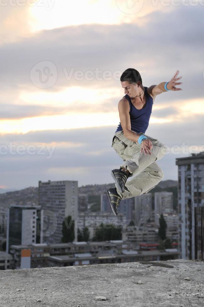 junger Mann springt nachts im Freien in die Luft und ist bereit für die Party foto