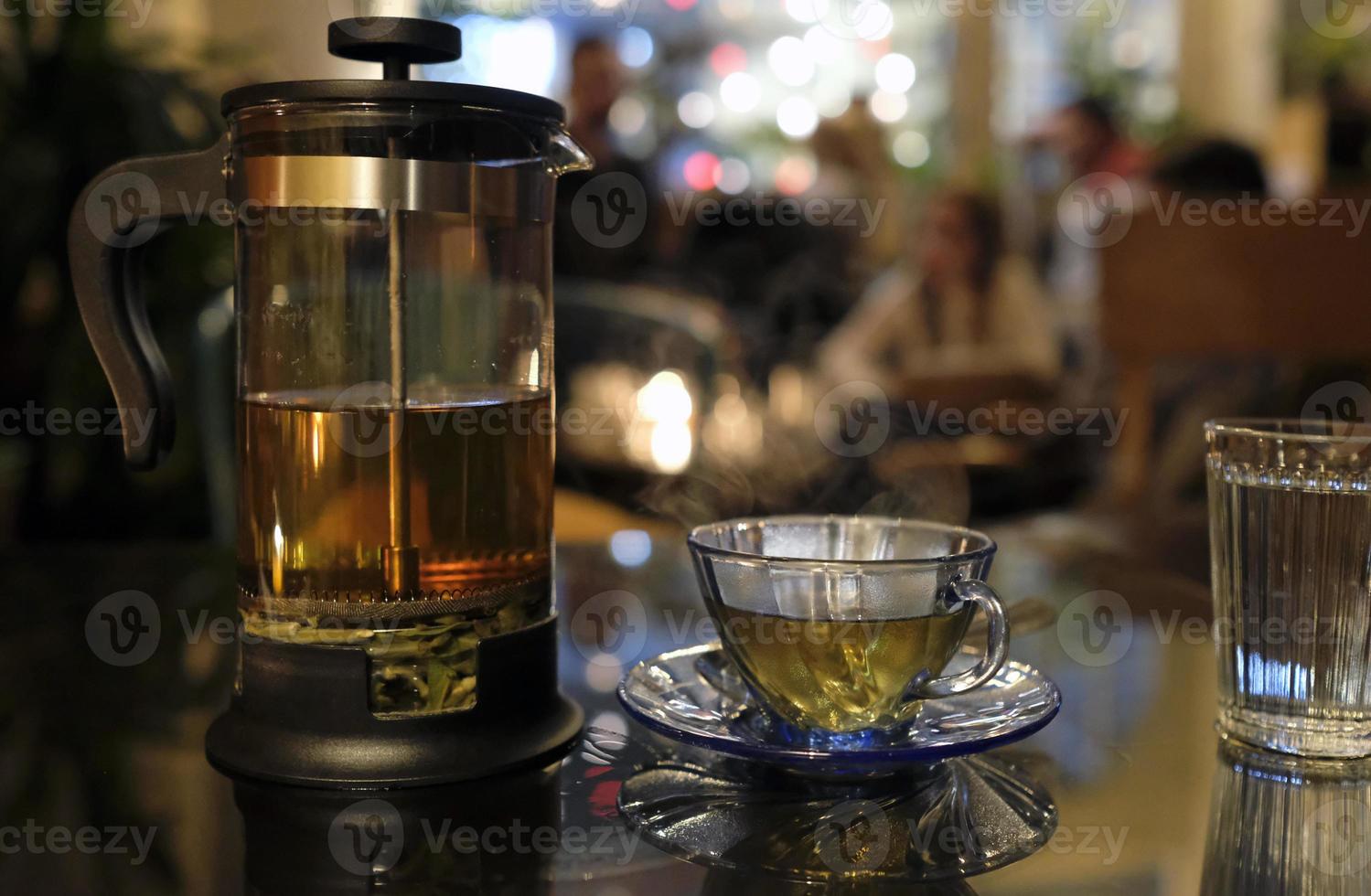 Abends frischer Kräutertee in einer transparenten Teepresse in einem gemütlichen Café foto