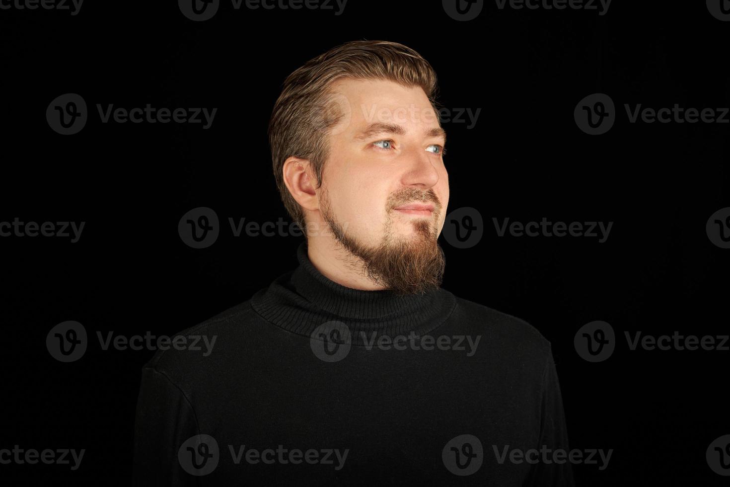 süßer bärtiger Mann, Halbprofilporträt, schwarzer Hintergrund foto