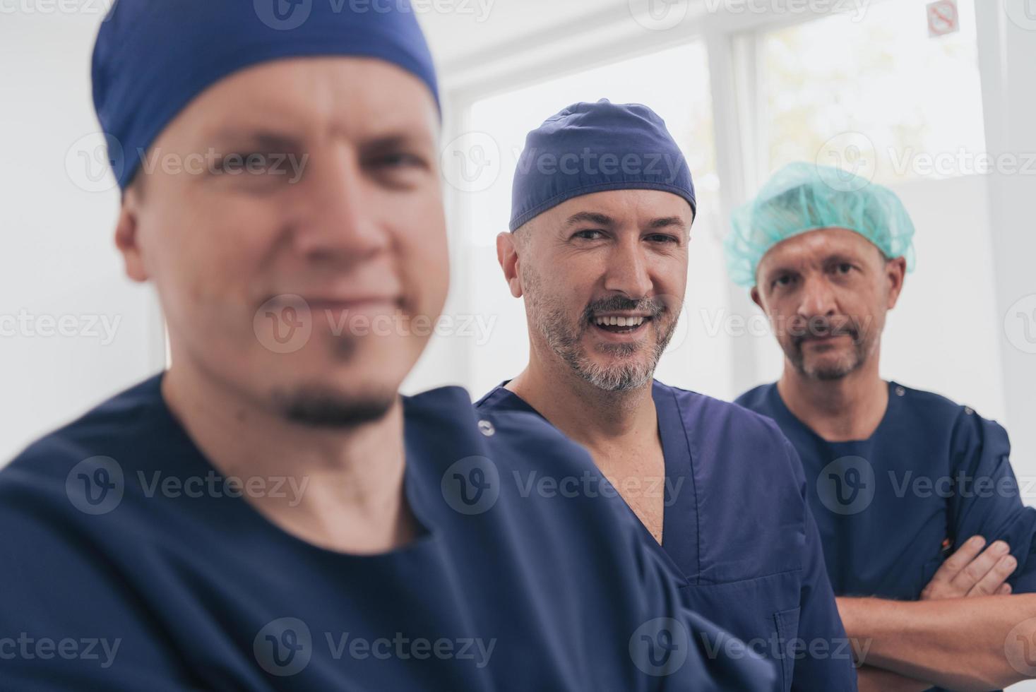multiethnischer Orthopäde vor seinem medizinischen Team, der mit Gesichtsmaske in die Kamera schaut foto