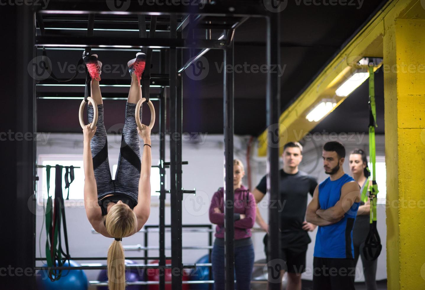 frau, die mit persönlichem trainer an gymnastikringen trainiert foto