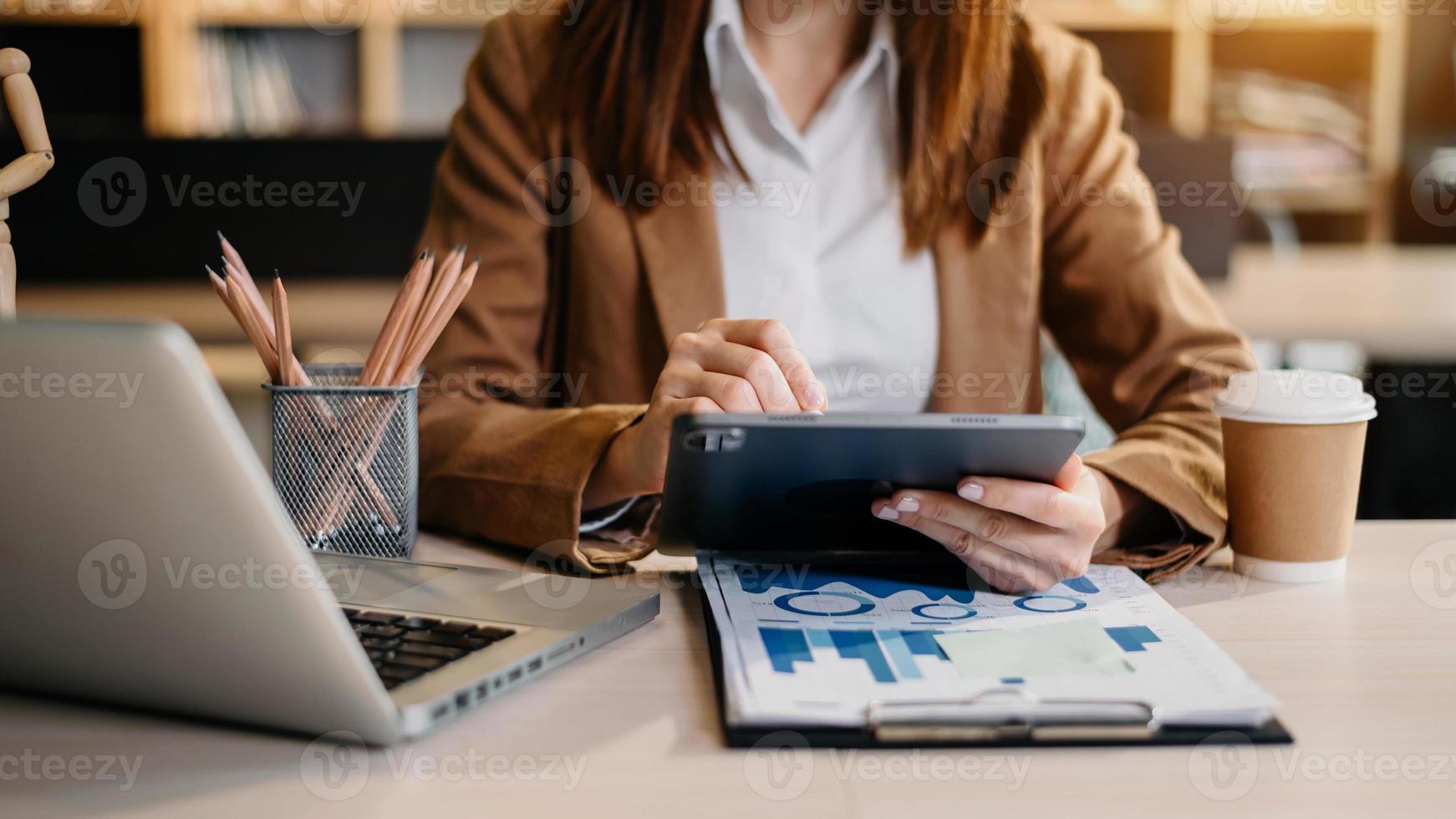 modedesigner l junge asiatische frau, die mit laptop, tablet und lächelt, während sie in der werkstatt steht und auf geschäftliche e-mails antwortet. foto