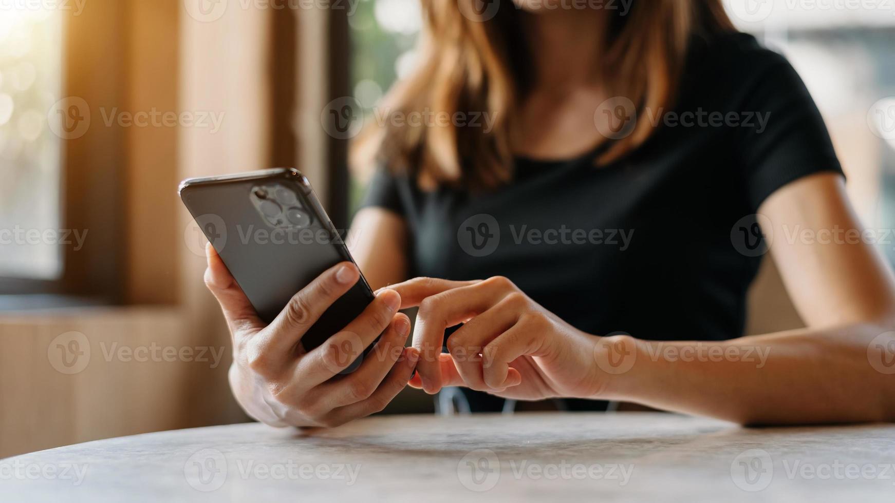 Frau mit Smartphone für mobile Zahlungen Online-Shopping, Omni-Kanal, Sitzen auf dem Tisch, virtuelle Symbole mit grafischer Benutzeroberfläche im Morgenlicht foto