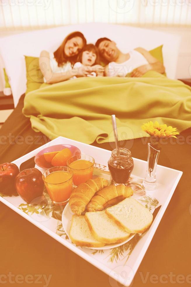 Glückliche junge Familie frühstückt im Bett foto