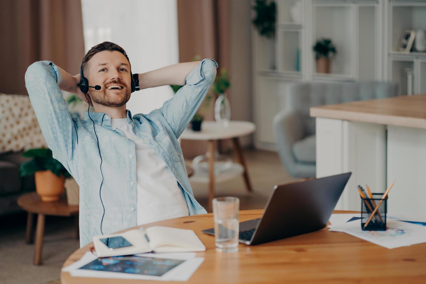 glücklicher kerl mit headset mit mikrofon, der online-video-chat genießt foto