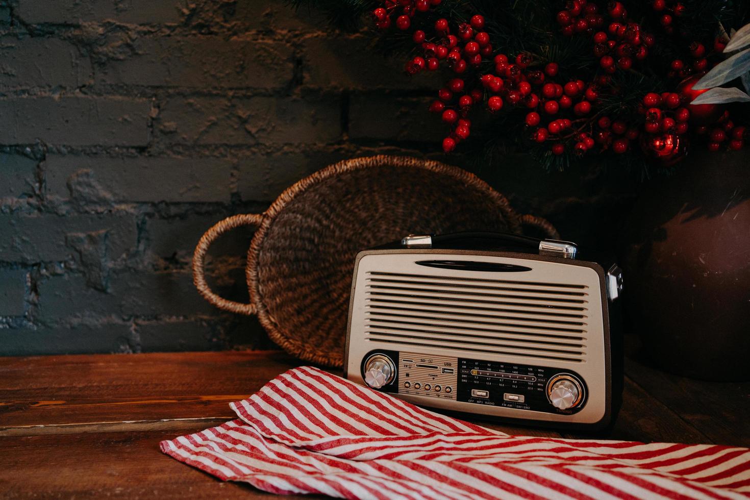 Retro-Radio auf Holztisch mit Weidenkorb und Blumendekor. Vintage-Stil. Antiker alter Rundfunkempfänger auf rustikalem Hintergrund. foto