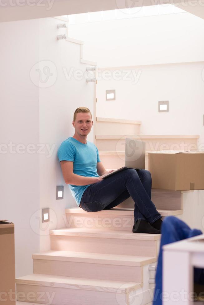 junger mann, der zu hause im treppenhaus sitzt foto