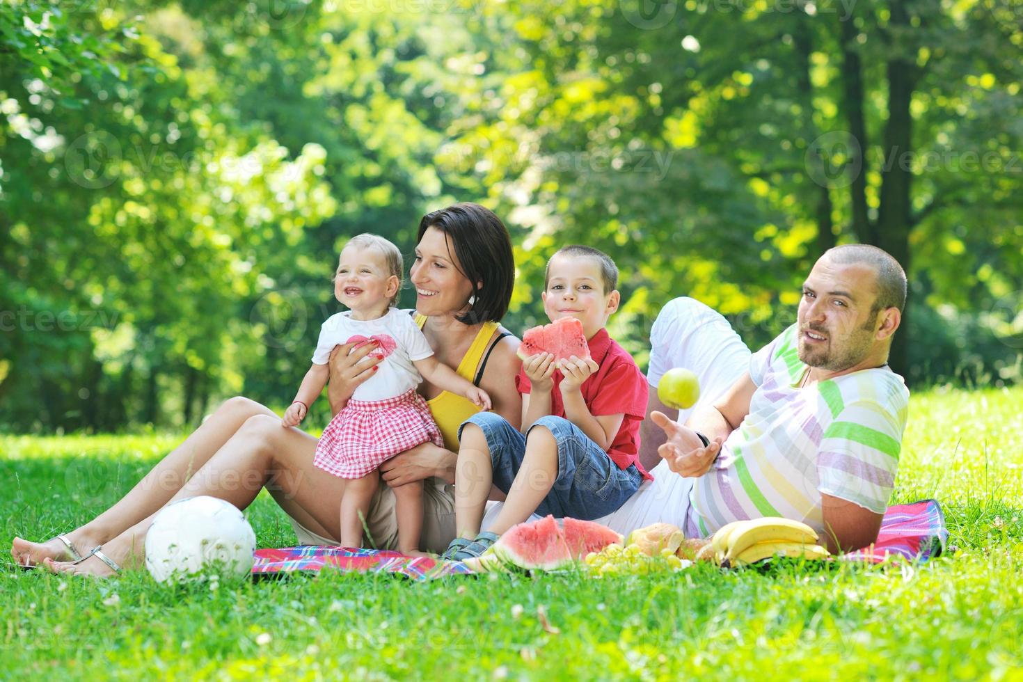 glückliches junges Paar mit ihren Kindern haben Spaß im Park foto