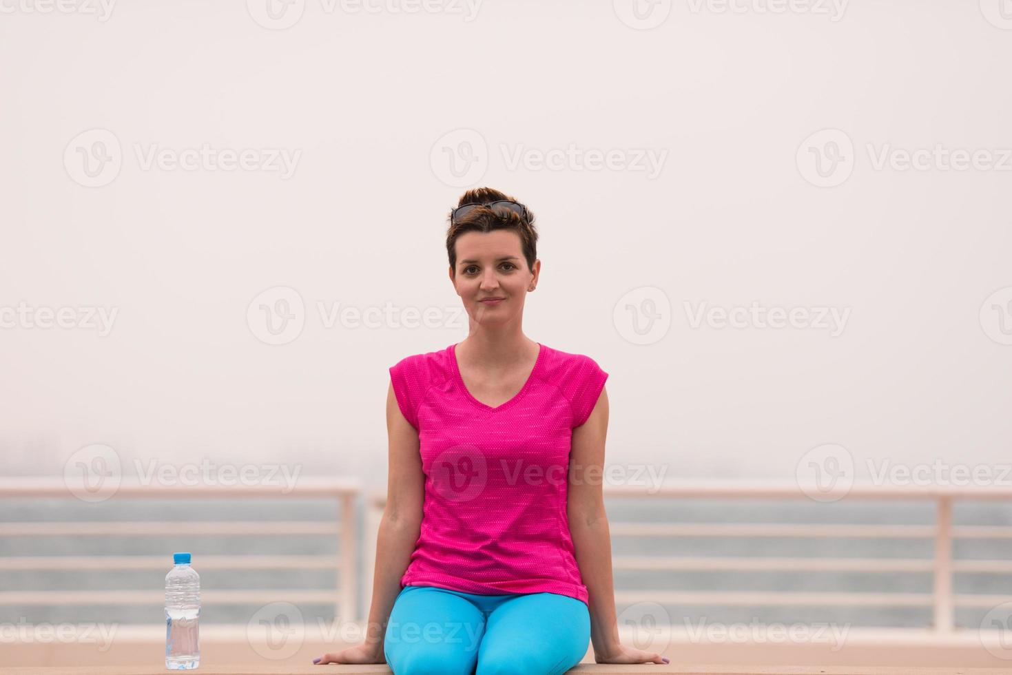 junge frau, die nach einem erfolgreichen trainingslauf sitzt foto