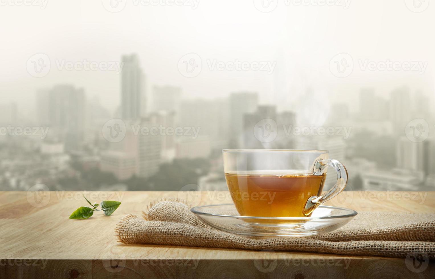 Tasse Tee mit Sackleinen auf dem Holztisch und dem Stadthintergrund foto