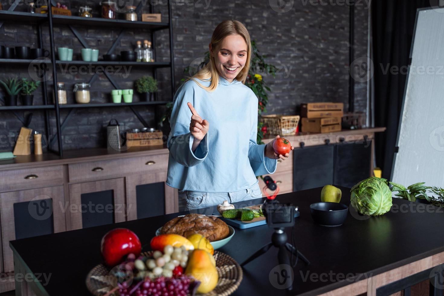 junge schöne Blondine nimmt Videos auf, während sie in der Küche kocht foto