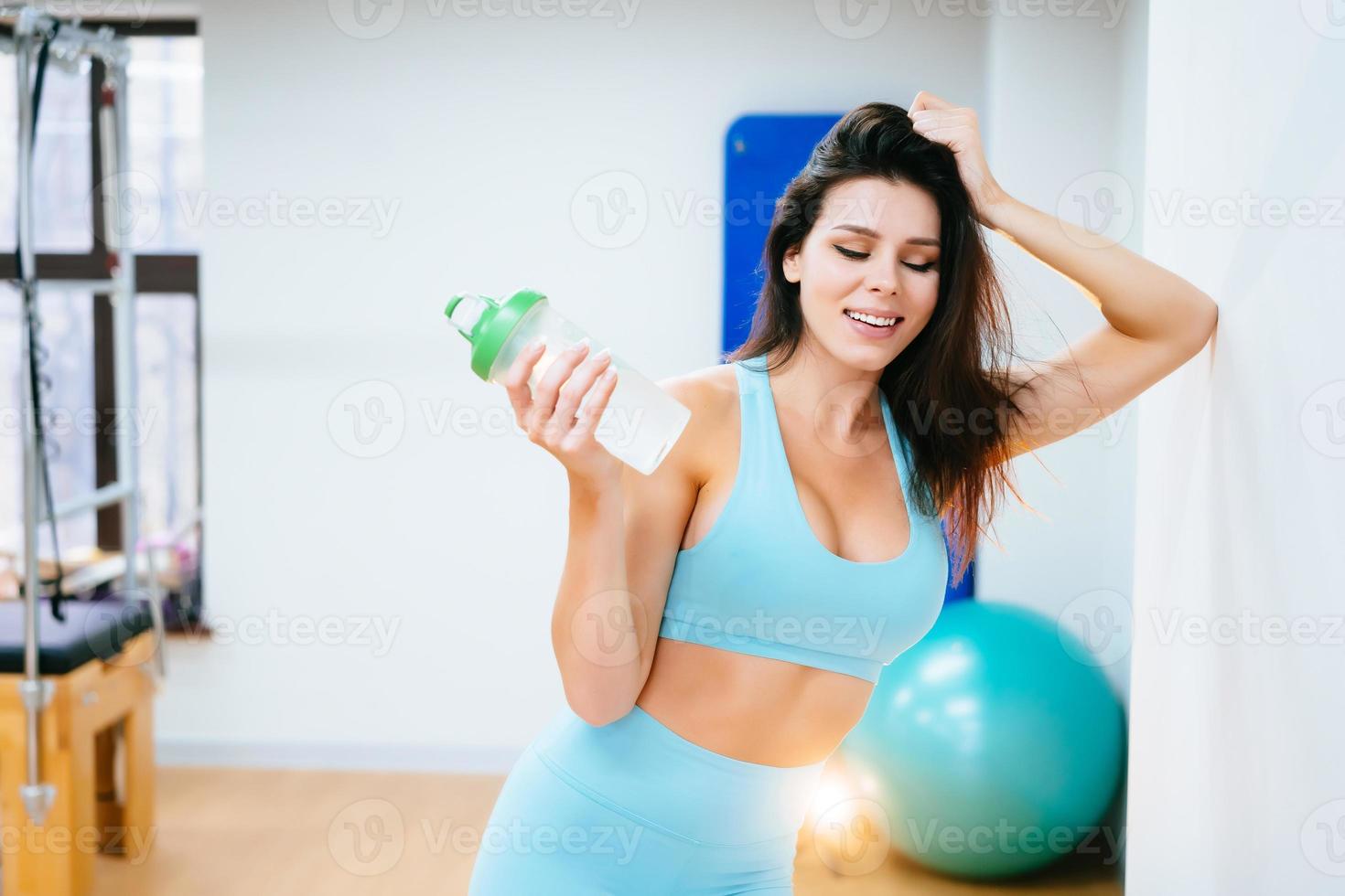 Sportlerin ruht und trinkt Wasser auf der Treppe im Fitnessstudio foto