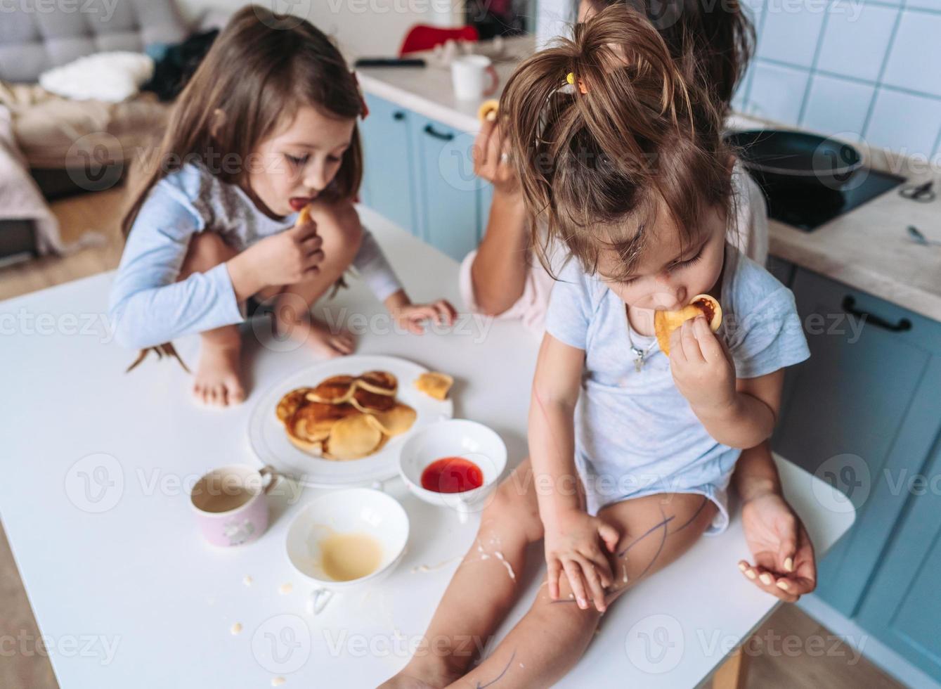 Mutter und zwei Töchter essen Pfannkuchen foto