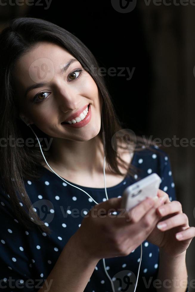 schönes Mädchen, das Musik am Telefon mit Kopfhörern hört foto