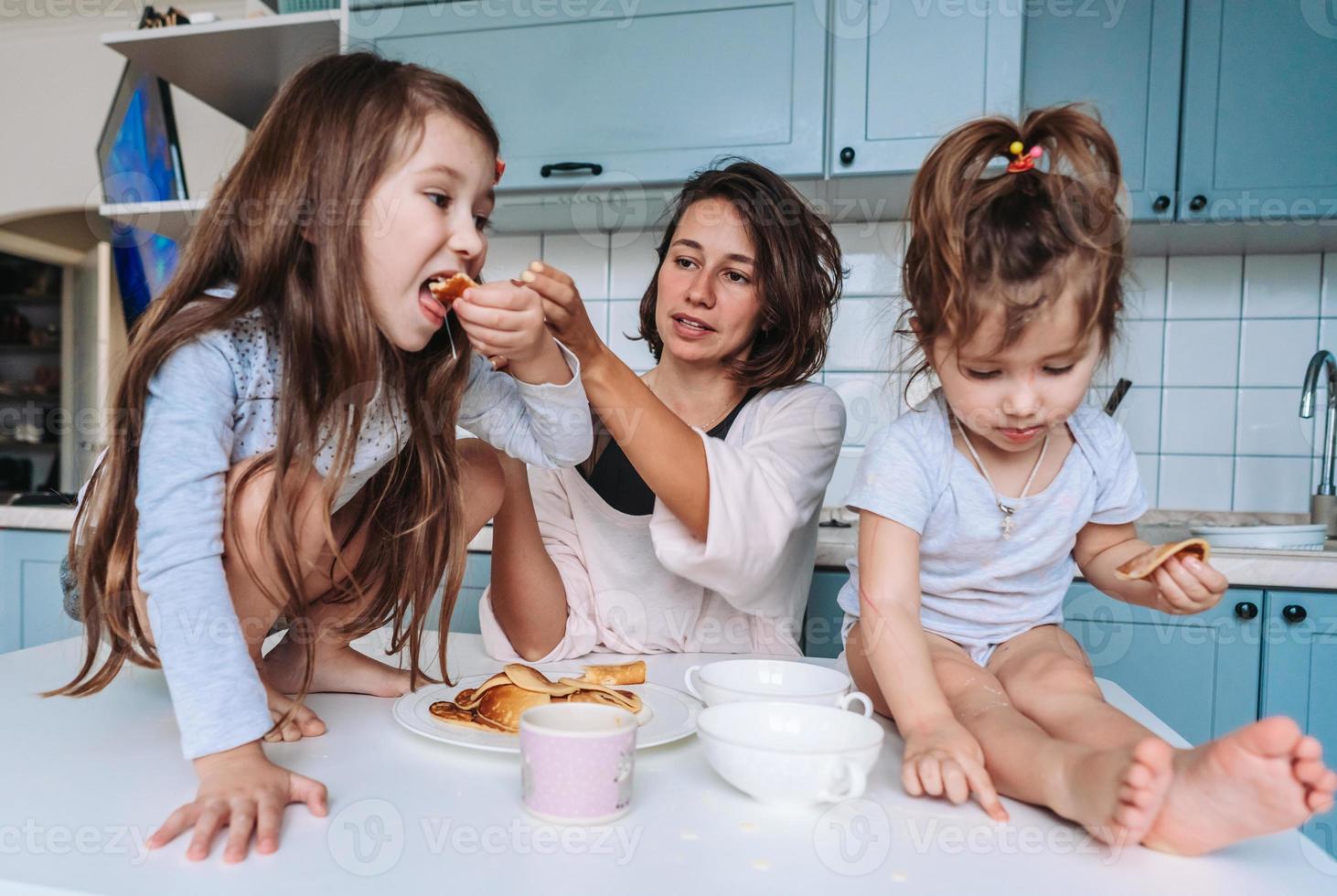 Mutter und zwei Töchter essen Pfannkuchen foto