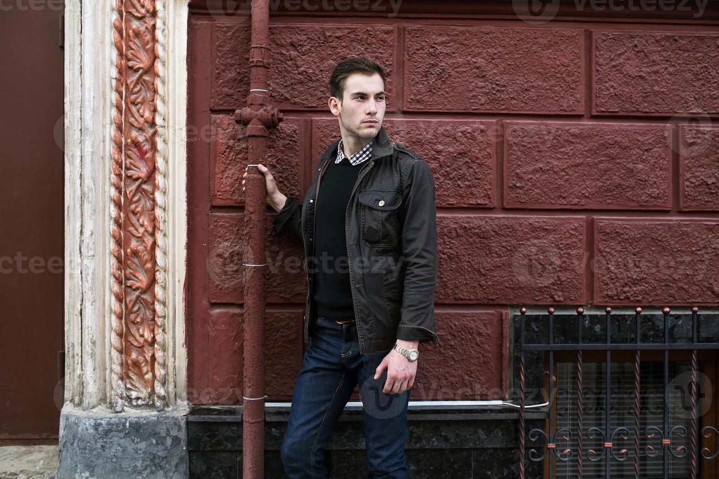 männliches Modell in Jeans auf dem Hintergrund einer roten Wand foto