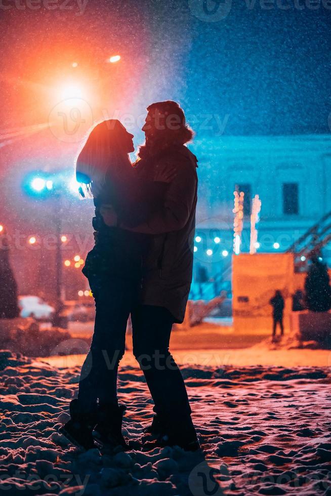 junges erwachsenes paar in den armen des anderen auf schneebedeckter straße. foto