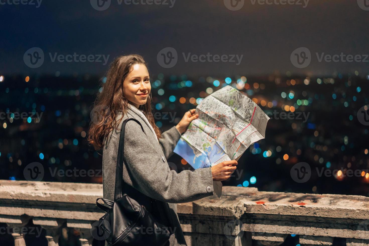 Mädchen mit einer Karte auf dem Hintergrund der Nachtstadt foto