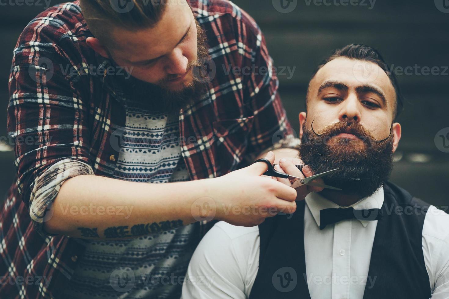 Friseur rasiert einen bärtigen Mann foto