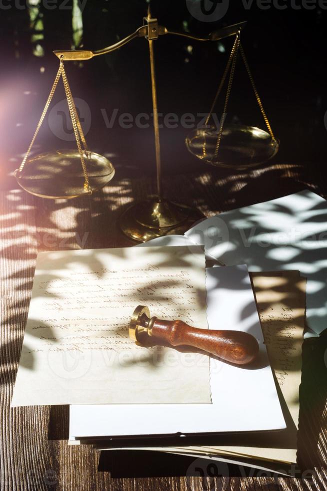 geschäftsleute und anwälte diskutieren vertragspapiere mit messingwaage auf dem schreibtisch im büro. gesetz, juristische dienstleistungen, beratung, justiz und gesetz konzeptbild mit filmkorneffekt foto