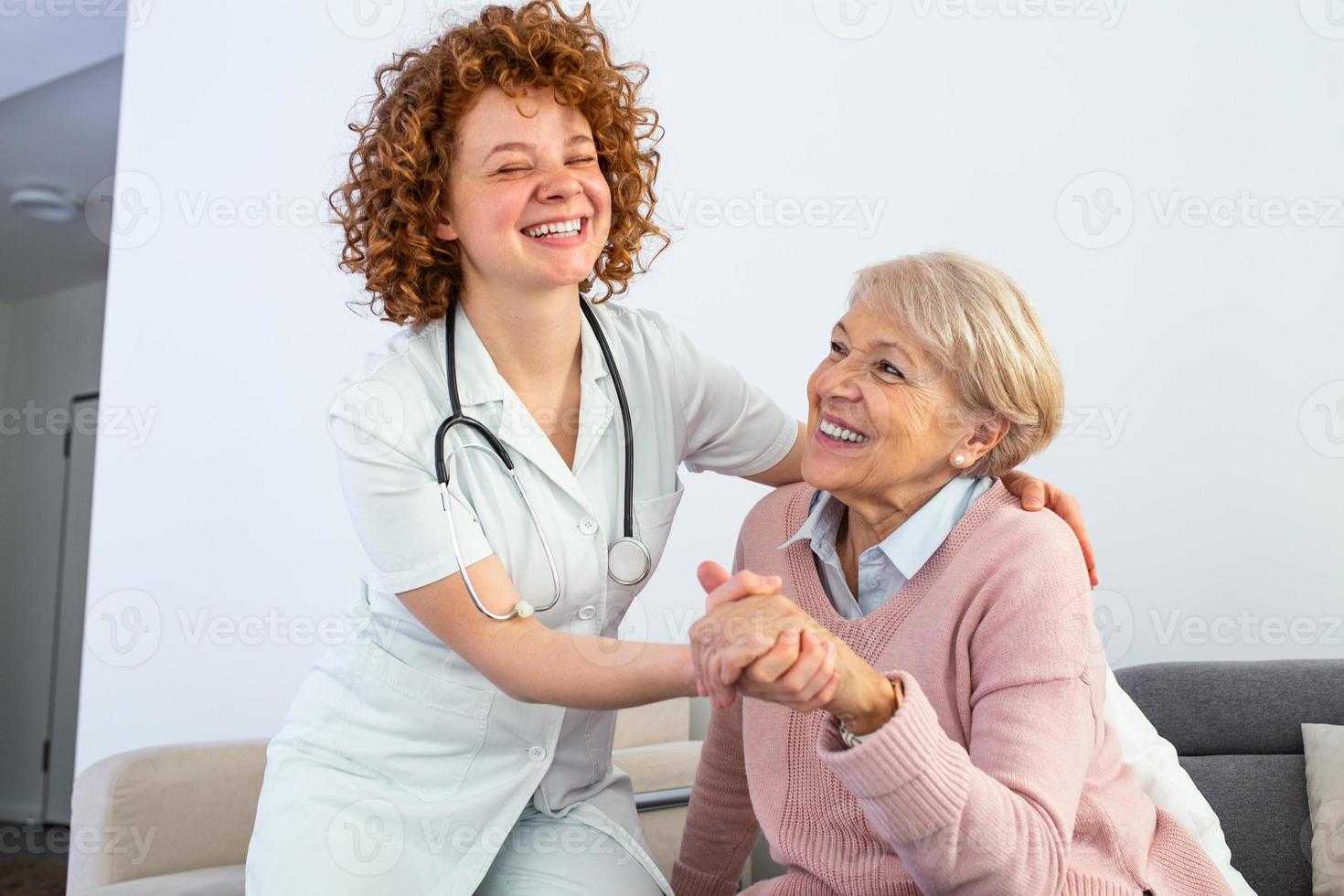 junge, fürsorgliche, nette Betreuerin und glückliche Gemeinde. Bild einer Pflegekraft und eines Senioren, die sich im Wohnzimmer ausruhen. lächelnde Pflegekraft, die sich um eine glückliche ältere Frau kümmert foto