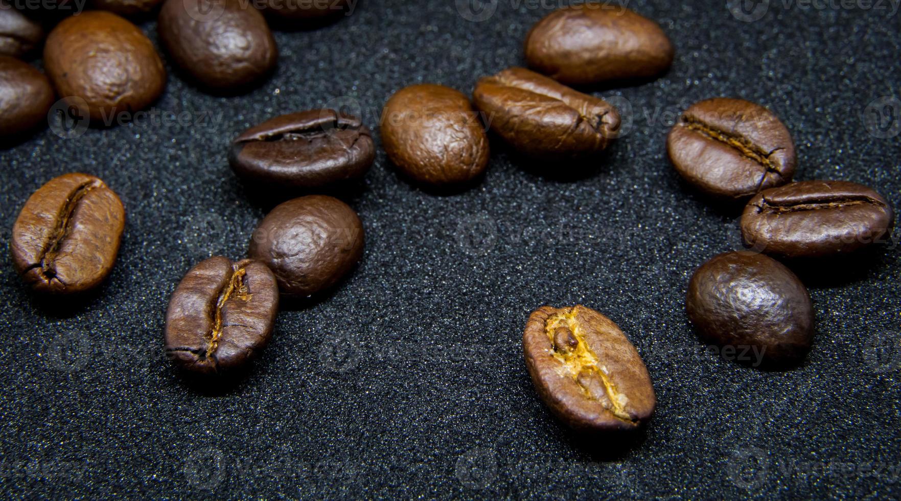 die Art und Weise, wie Kaffeebohnen auf einem schwarzen Hintergrund liegen, elegante und köstliche Kaffeebohnen und das Aroma von Morgenkaffee. foto