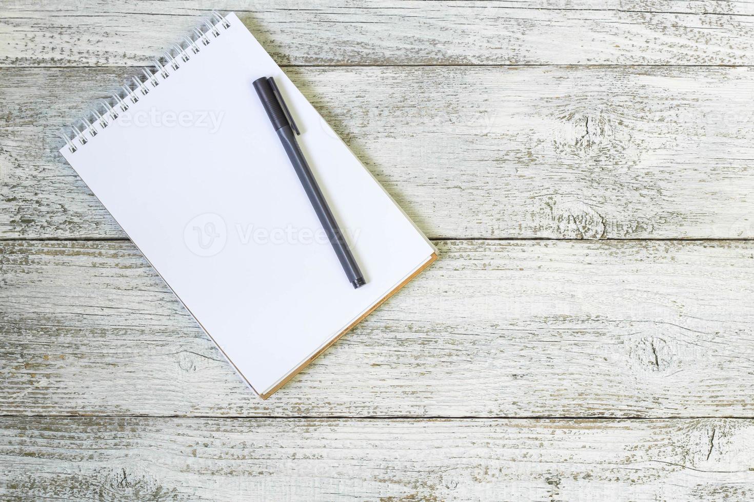 Stift und Notizblock auf dem weißen Holztisch foto