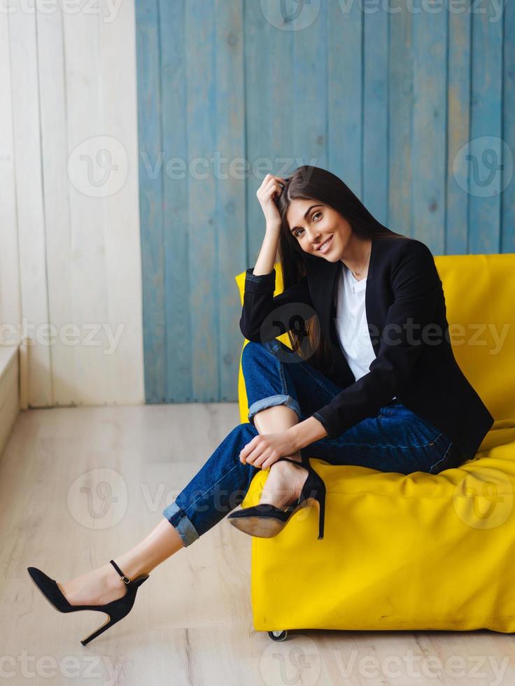 junge Frau sitzt auf gelbem Sofa foto