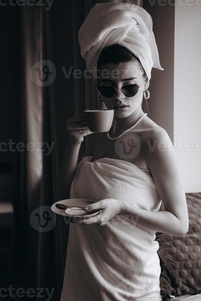 Mädchen in ein Handtuch gewickelt nach einer Dusche Kaffee trinken foto