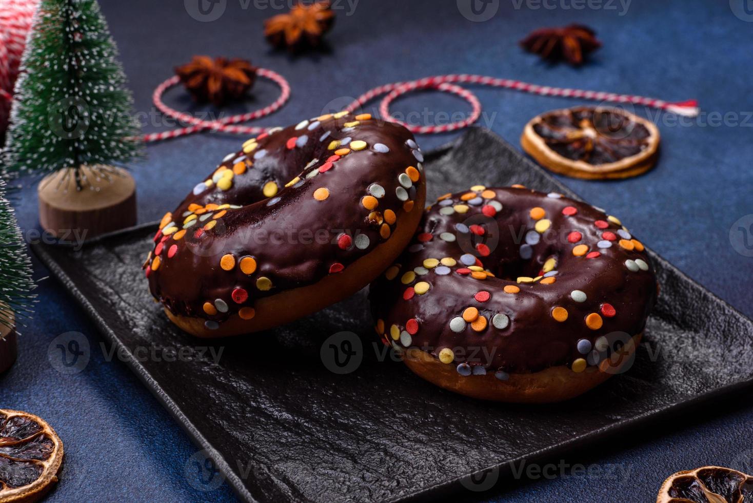 Gebäck-Konzept. Donuts mit Schokoladenglasur mit Streuseln, auf einem dunklen Betontisch foto