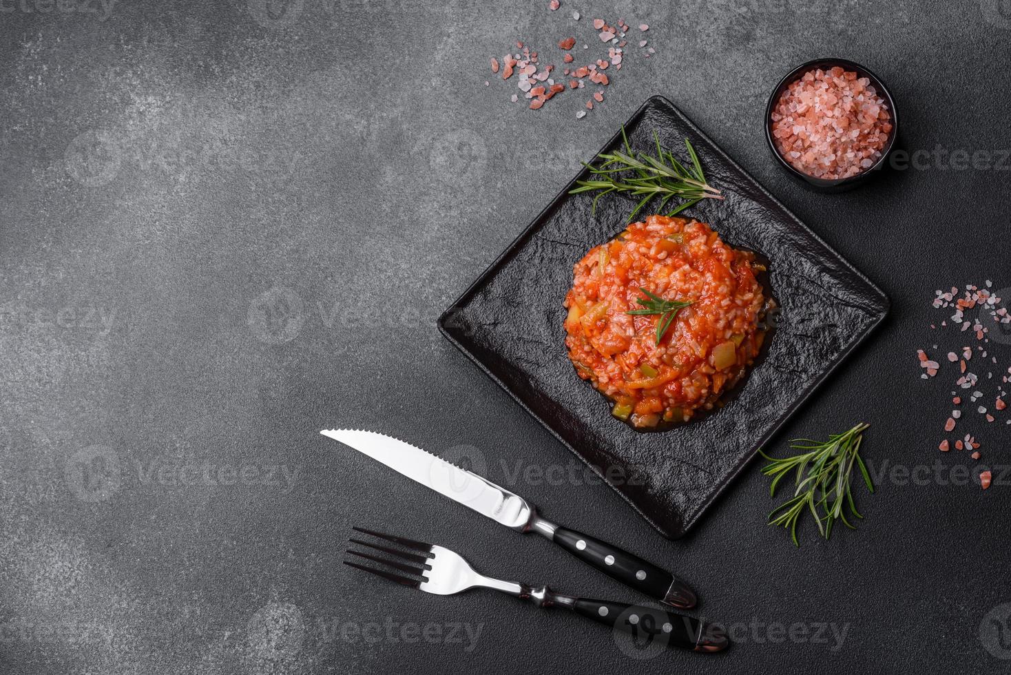 gekochter Reis mit Paprika, Gewürzen, Kräutern und Tomatensauce auf einer schwarzen Schieferplatte foto