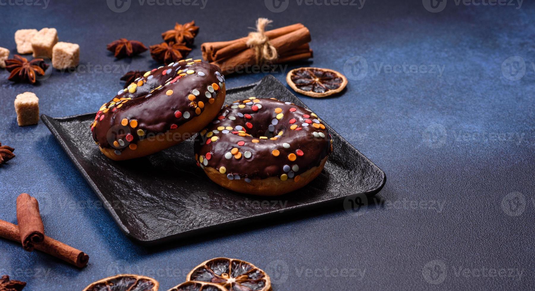 Gebäck-Konzept. Donuts mit Schokoladenglasur mit Streuseln, auf einem dunklen Betontisch foto