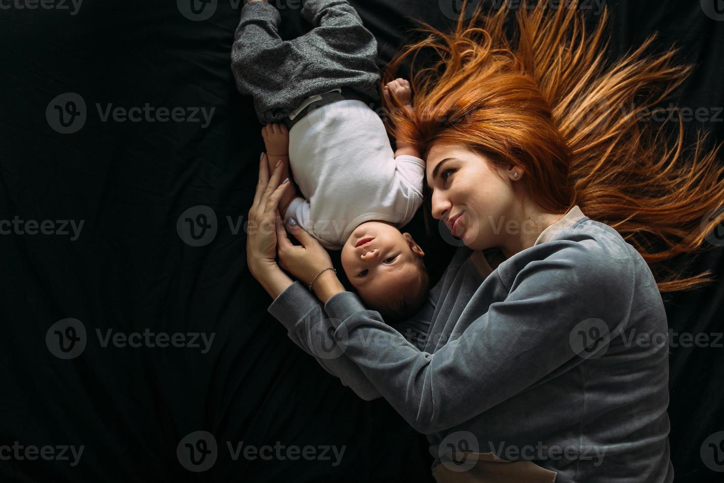 glückliche Mutter mit Baby, die zusammen auf dem Bett liegt foto