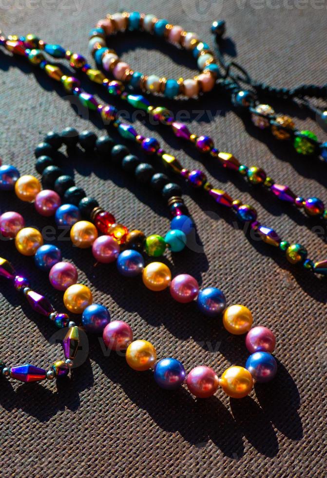 Haufen farbiger heller Schmuckperlen auf dunklem Hintergrund. verschiedene edelsteine perlen halskette. Juwel Halskette modernes Modemuster oder Textur. Schmuck Hintergrund foto