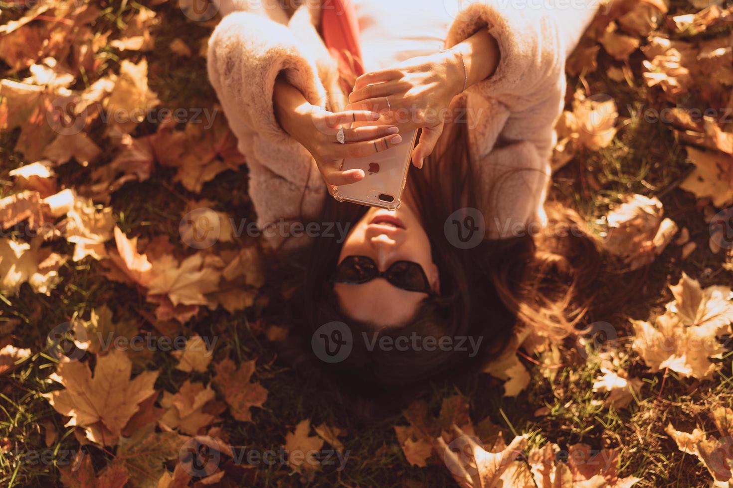 Draufsicht der schönen jungen Frau liegt auf Herbstlaub foto