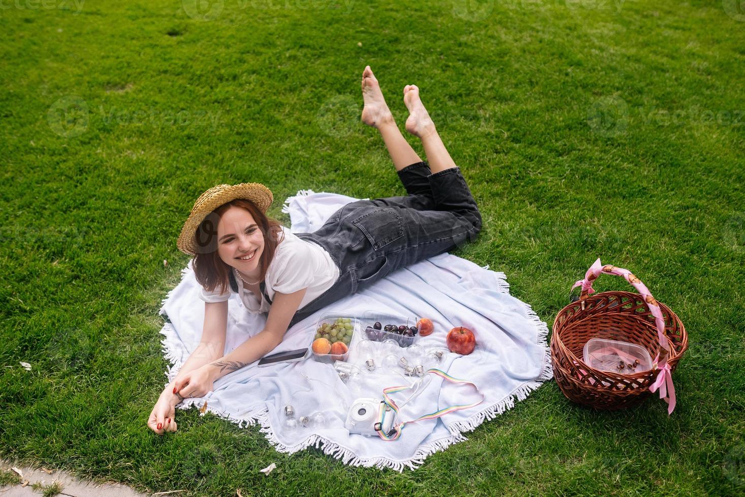 glückliche junge frau, die auf einer decke auf dem parkrasen liegt foto