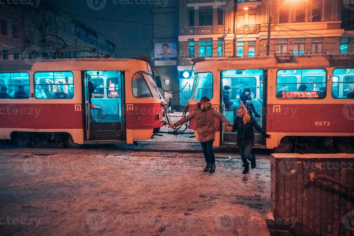 junges erwachsenes paar auf schneebedeckter straßenbahnstation foto