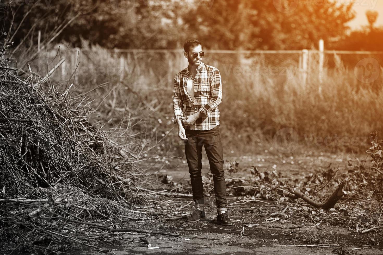 der Mann in den authentischen Stiefeln und Selvedge-Jeans auf dem Hintergrund von Ästen foto