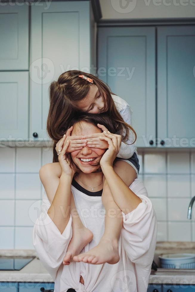 schöne kleine tochter, die ihre glückliche mutter huckepack trägt foto