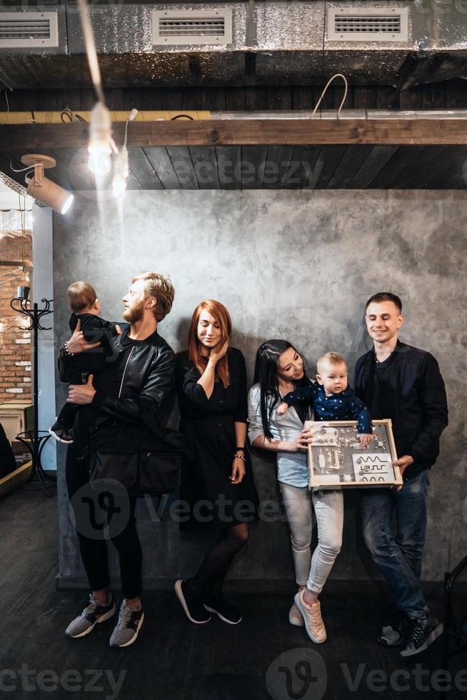 Zwei junge Familien posieren vor einer grauen Wand foto