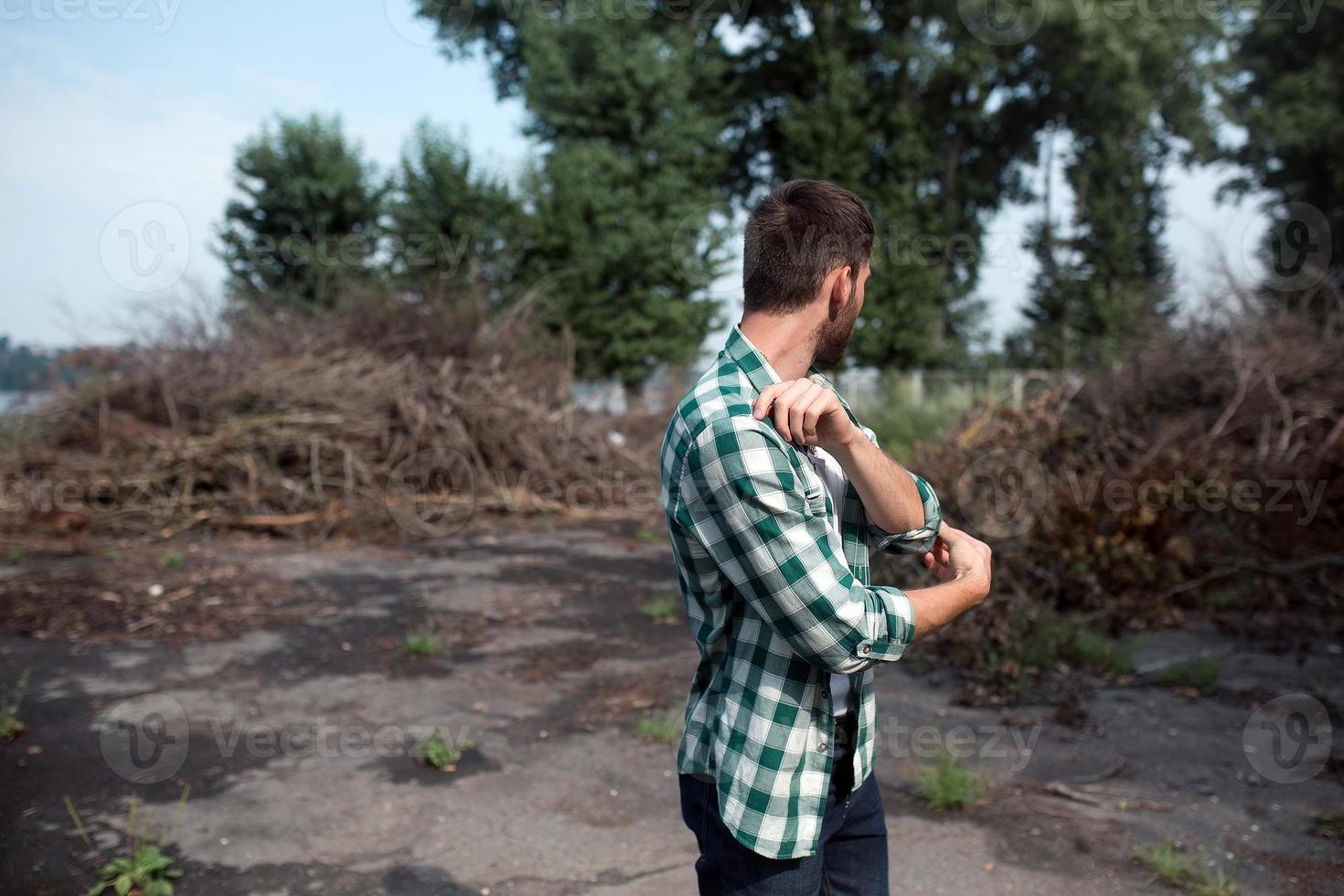 der Mann in den authentischen Stiefeln und Selvedge-Jeans auf dem Hintergrund von Ästen foto