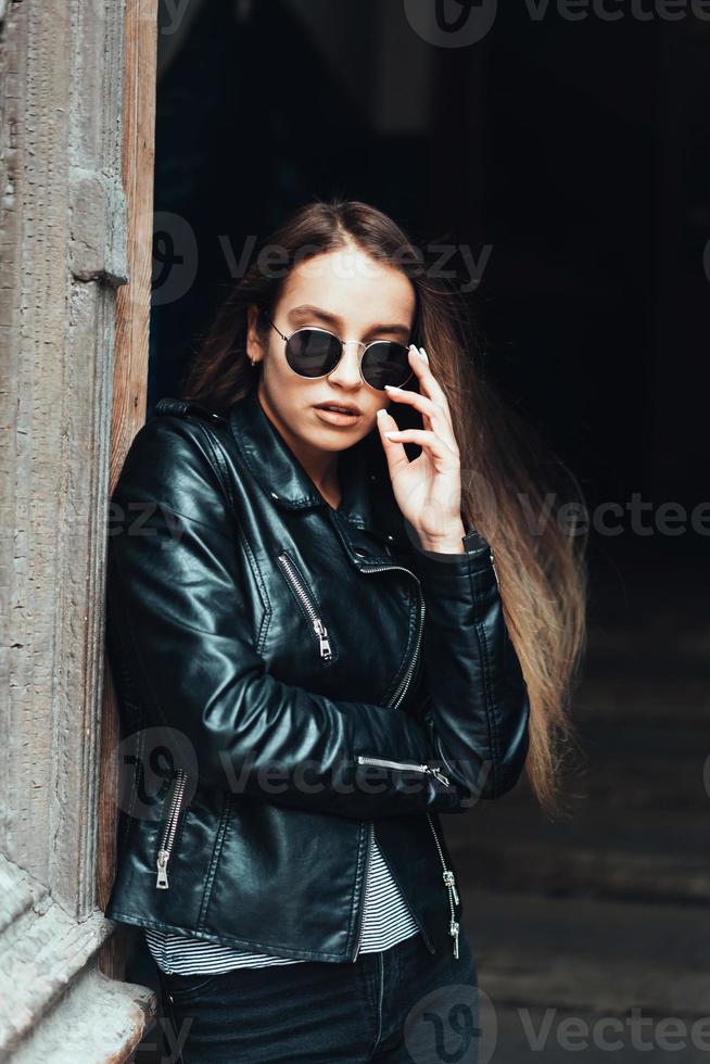 schönes Mädchen in einer schwarzen Jacke und Sonnenbrille foto
