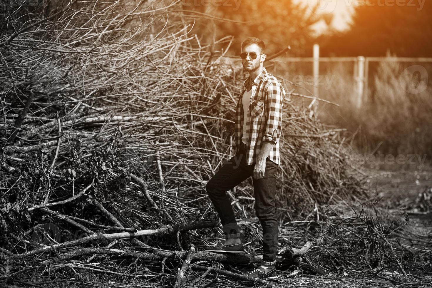 der Mann in den authentischen Stiefeln und Selvedge-Jeans auf dem Hintergrund von Ästen foto