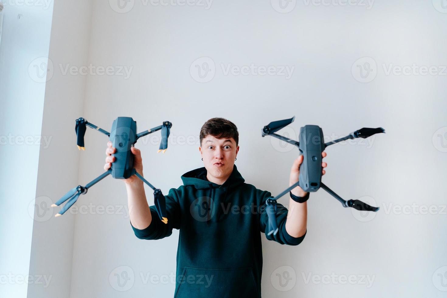 Typ hält zwei Quadrocopter gegen eine Wand foto